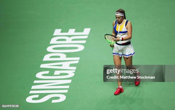 Jelena Ostapenko of Latvia adjusts her racquet between points while playing Garbine Muguruza of Spain during day 1 of the BNP Paribas WTA Finals...