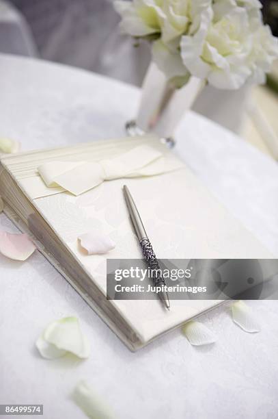 guest book on table with flowers and petals - gastenboek stockfoto's en -beelden