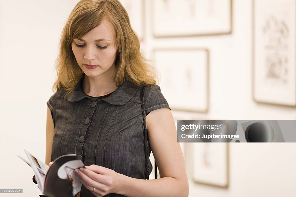 Woman reading booklet in art gallery