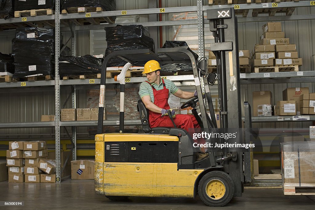 Worker with forklift moving boxes