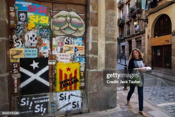 Woman walks past pieces of Catalan pro-independence graffiti on some doors on October 22, 2017 in Barcelona, Spain. The Spanish government is to take...