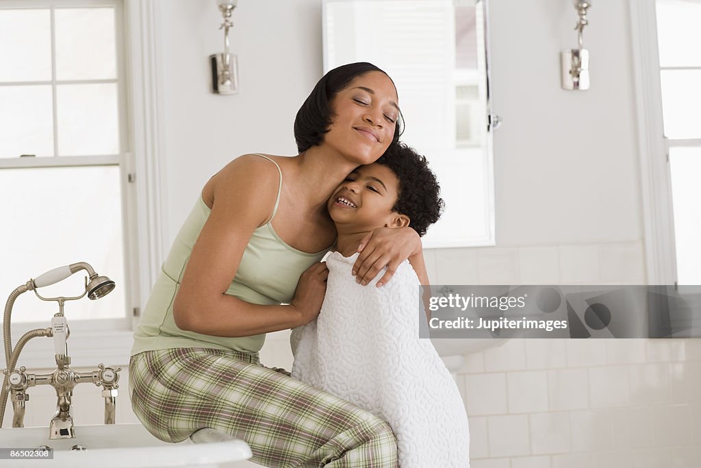 Mother hugging son in bathroom