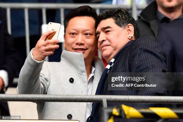 Argentinian legend Diego Maradona poses for a selfie photograph ahead of the English Premier League football match between Tottenham Hotspur and...