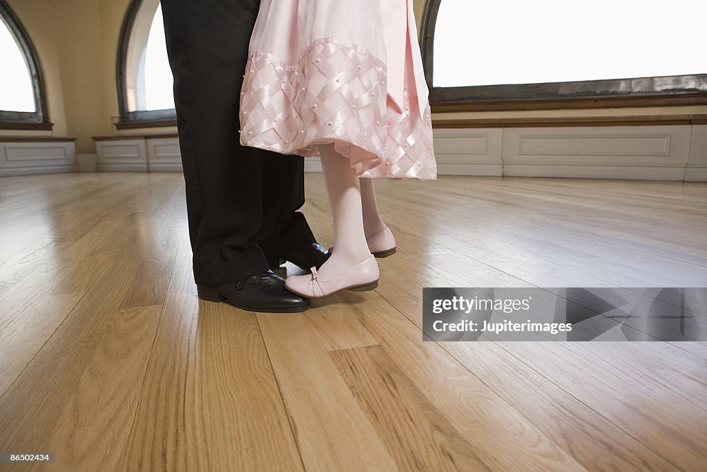 Daughter standing on feet of father dancing
