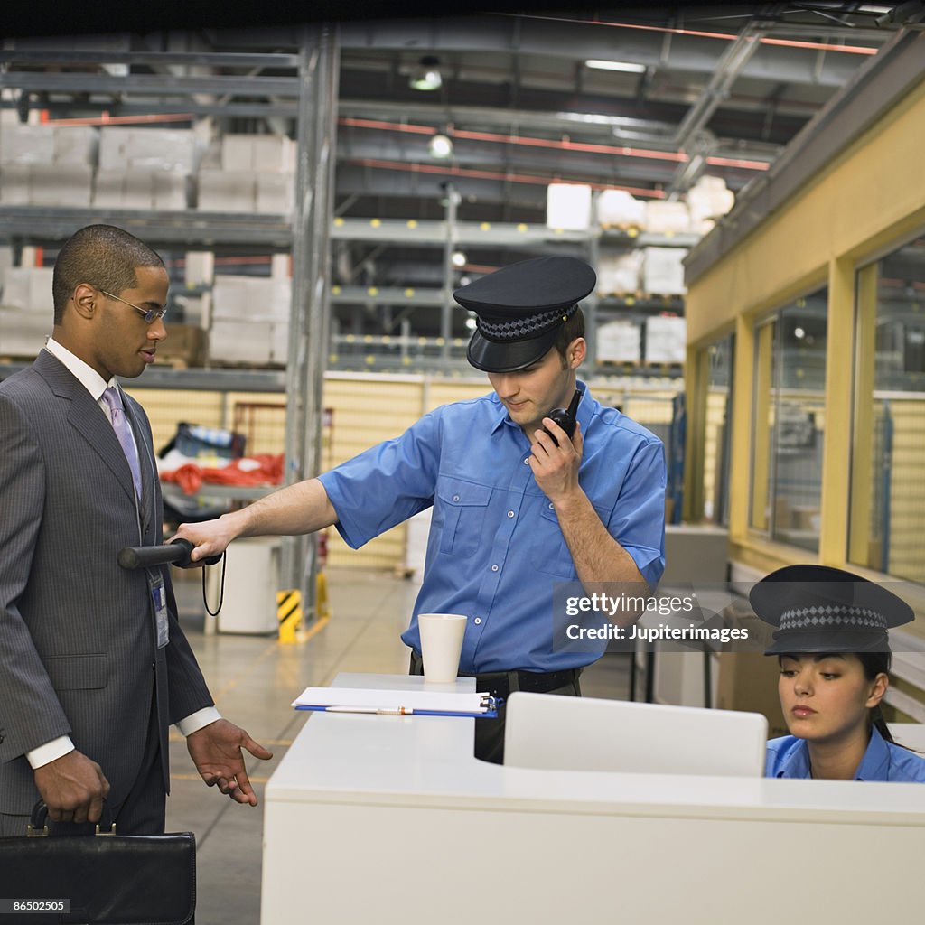 Security guard scanning businessman