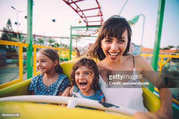 kleine zoon en dochter bij moeder op de roller coaster rit - pret stockfoto's en -beelden