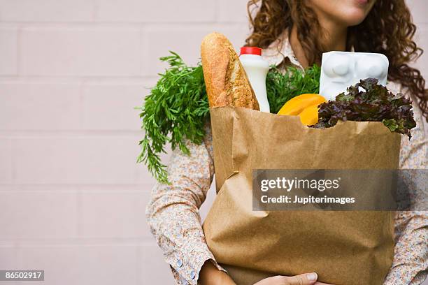 woman carrying a bag of groceries - shopping paper bag stock-fotos und bilder