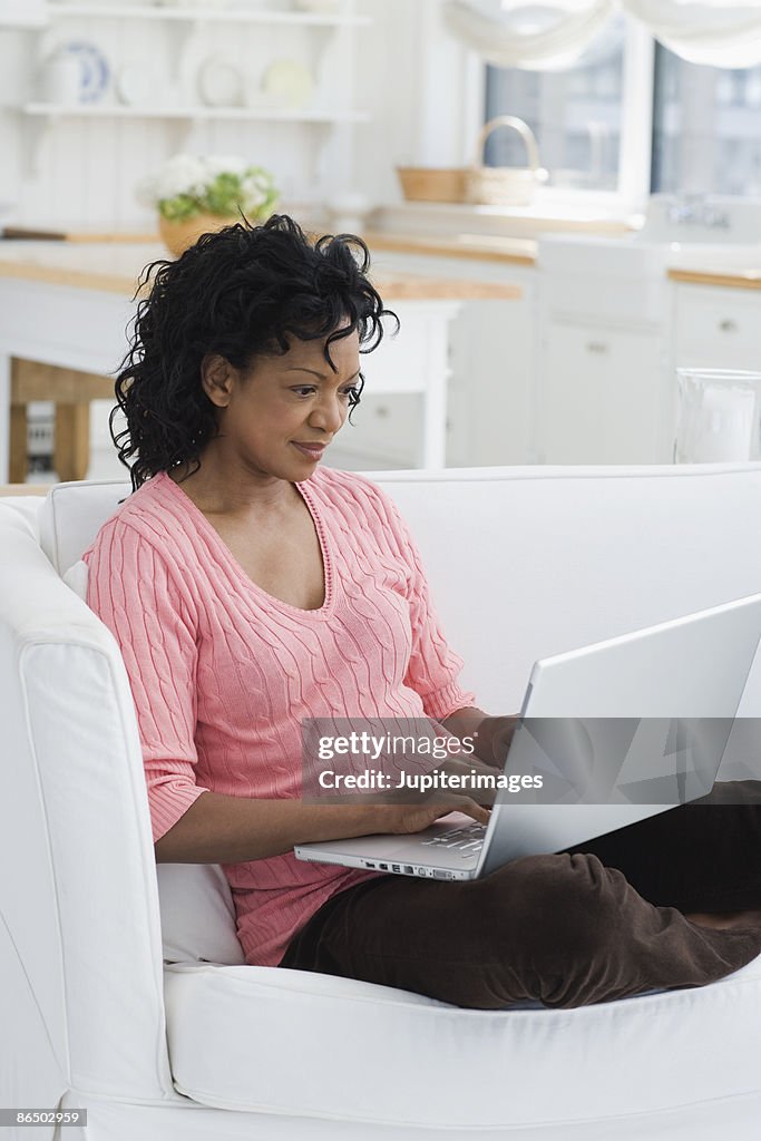 Woman sitting on couch and using laptop computer