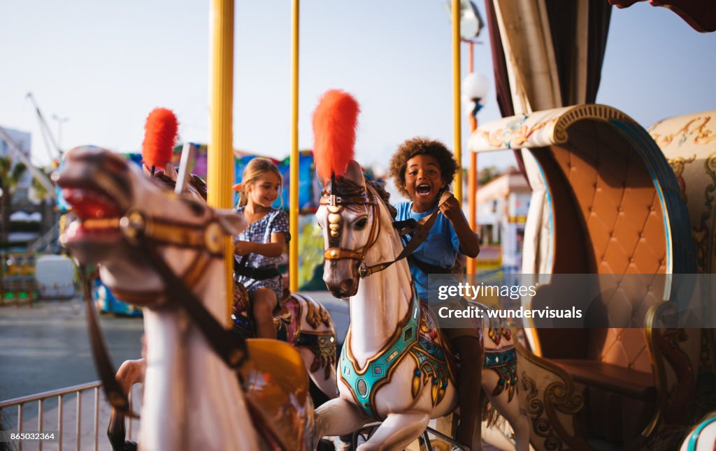 Multi-ethnic children having fun on funfair merry-go-round carousel ride