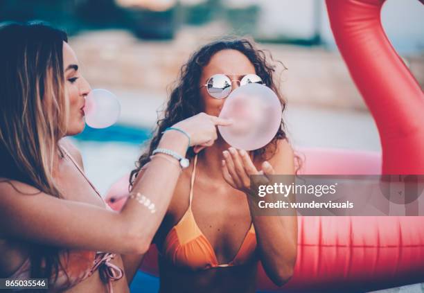 joven mujer multiétnica soplar chicles en la piscina con hinchables - mujer seductora fotografías e imágenes de stock