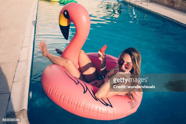 young woman with watermelon floating on inflatable flamingo in pool - model eating stock pictures, royalty-free photos & images