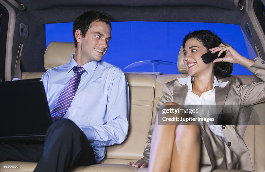 Businesspeople with laptop in backseat