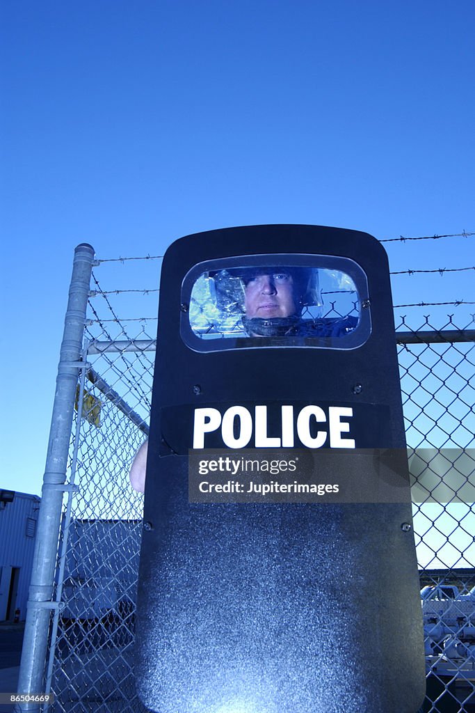 Policeman wearing a helmet and holding a shield