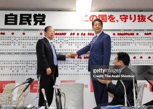 Japanese Prime Minister and ruling Liberal Democratic Party President Shinzo Abe and secretary general Toshihiro Nikai put a paper rose onto the...