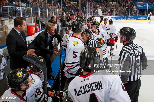 Linesman Tim Plamondon and referee Jeff Ingram stand on the ice at the Portland Winterhawks' bench and speak to head coach Mike Johnston and...