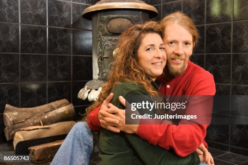 Couple embracing by wood stove Couple embracing by wood stove