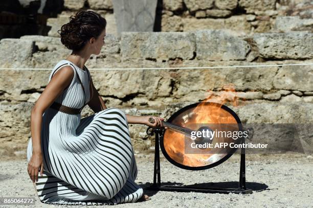 Actress Katerina Lechou acting the high priestess lights the Olympic flame at the Temple of Hera on October 22, 2017 during a dressed rehearsal of...