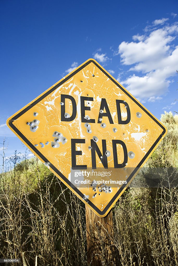 Dead end sign with bullet holes