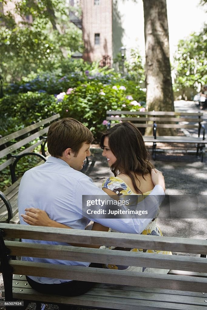 Romantic couple sitting on bench in park, New York City