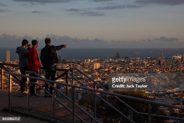 Group watches and takes pictures as the sun sets over the city on October 22, 2017 in Barcelona, Spain. The Spanish government is to take steps to...