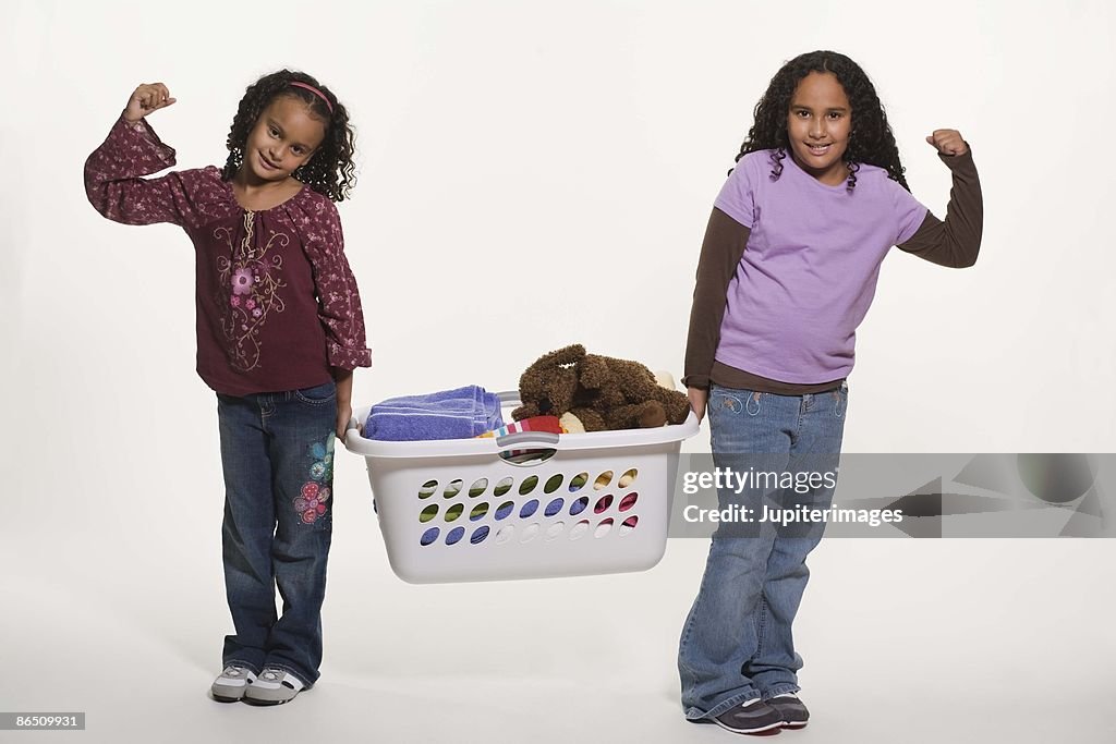 Girls lifting laundry basket