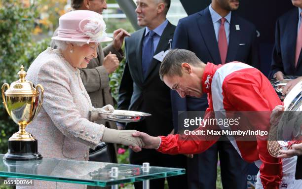 Queen Elizabeth II presents jockey Frankie Dettori with his prize for winning the Queen Elizabeth II Stakes on 'Persuasive' as she attends the QIPCO...