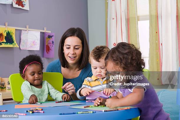 teacher and toddlers in daycare - puériculture stock pictures, royalty-free photos & images