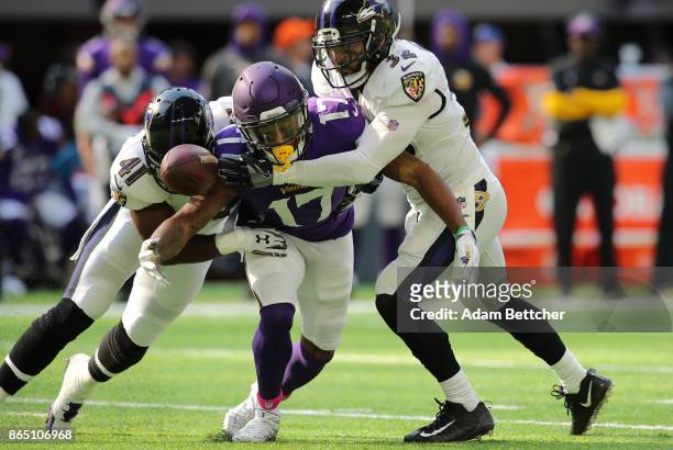 Jarius Wright of the Minnesota Vikings has the ball knocked loose by defenders Anthony Levine and Eric Weddle of the Baltimore Ravens in the second...