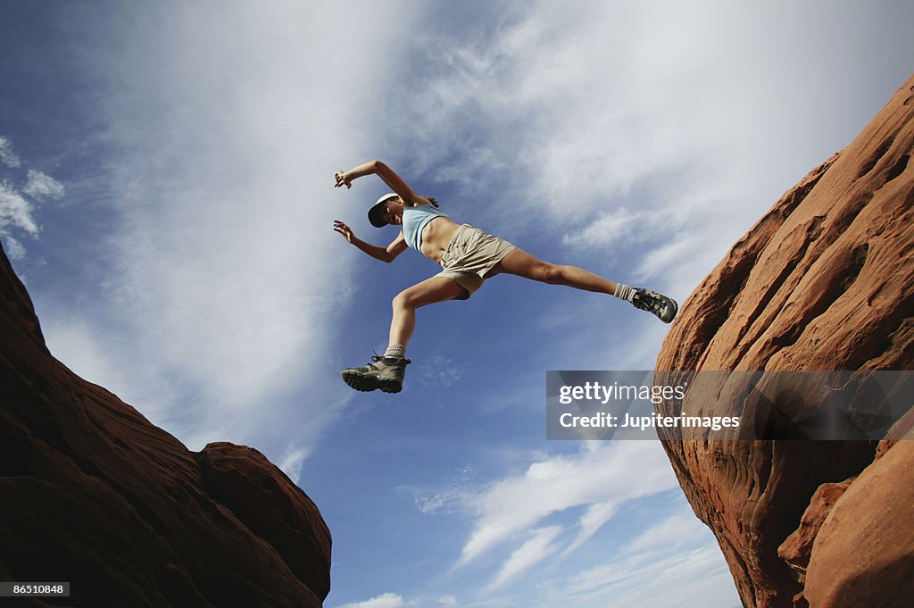 Woman jumping over rock ledge