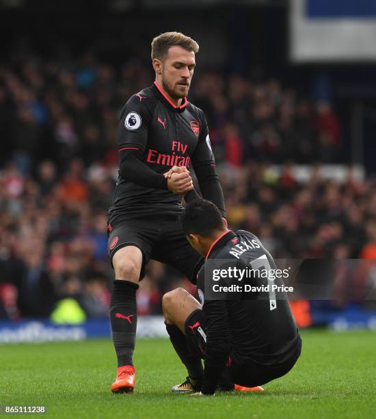 Aaron Ramsey helps up Alexis Sanchez of Arsenal during the Premier League match between Everton and Arsenal at Goodison Park on October 22, 2017 in...