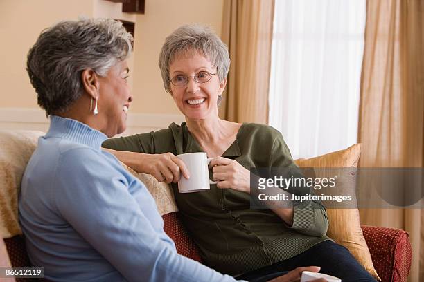 women talking on couch - two women talking stockfoto's en -beelden