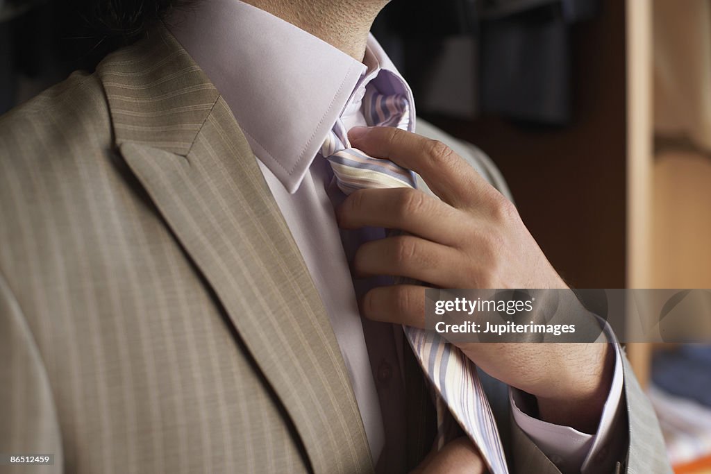 Man adjusting tie