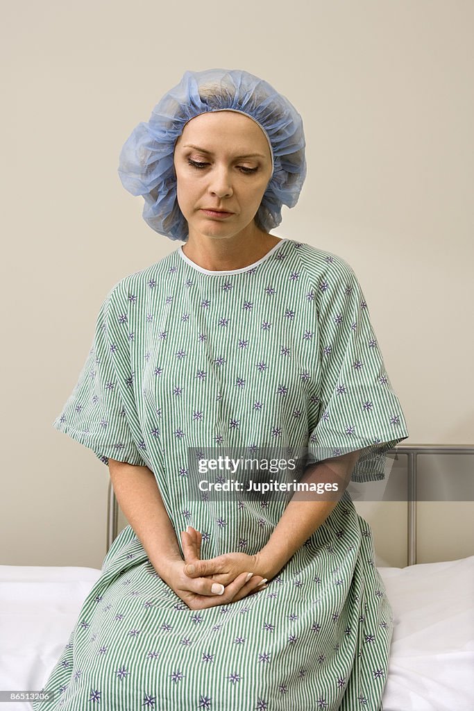 Woman looking down in hospital gown