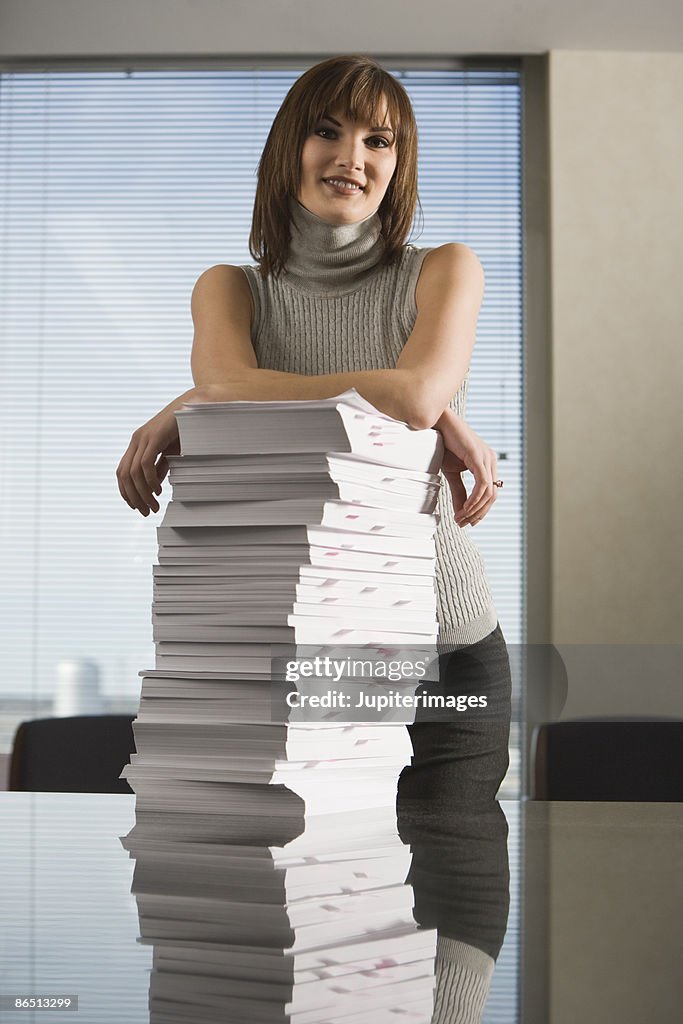 Portrait of businesswoman with stack of paperwork