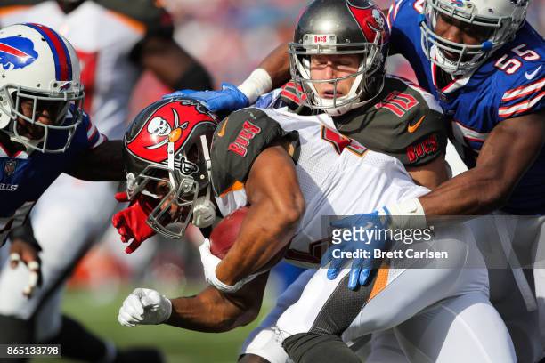 Doug Martin of the Tampa Bay Buccaneers runs the ball as he is tackled by Leonard Johnson and Jerry Hughes of the Buffalo Bills during the third...