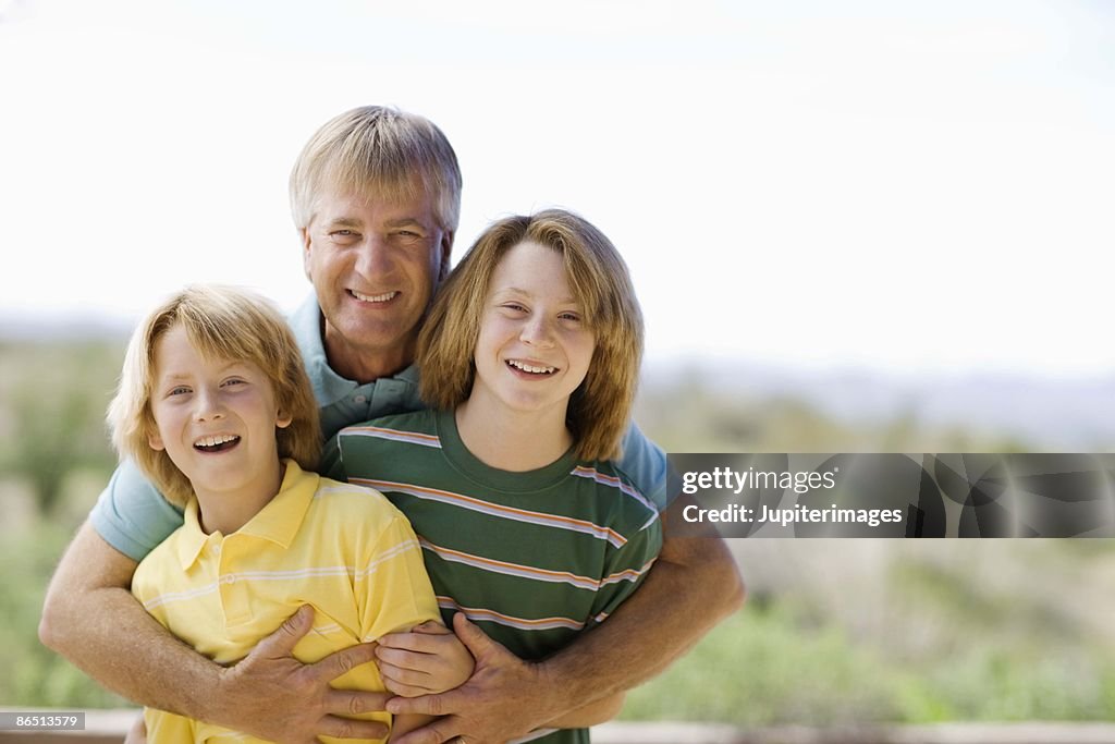 Father and sons embracing outdoors