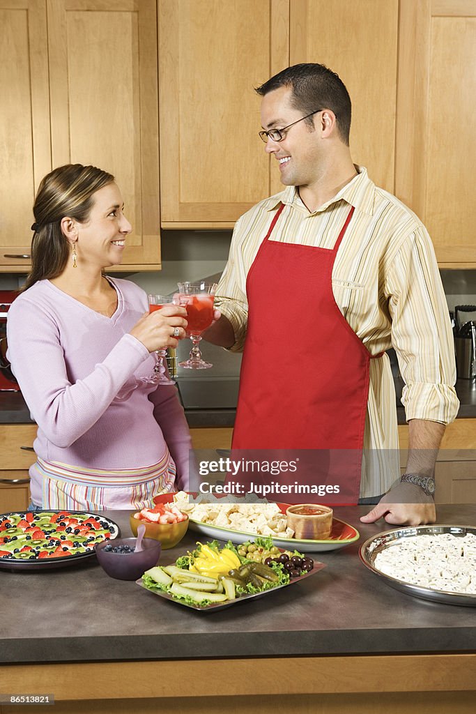 Couple toasting drinks in kitchen