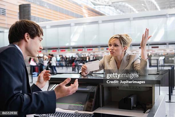 upset businesswoman checking in at airport ticket counter - airport frustration stock pictures, royalty-free photos & images