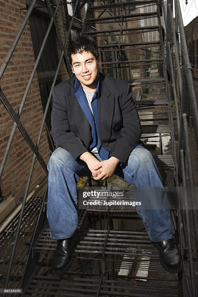 Man sitting on stairs of fire escape