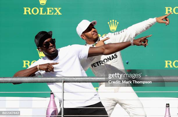 Race winner Lewis Hamilton of Great Britain and Mercedes GP celebrates on the podium with sprinting legend Usain Bolt during the United States...