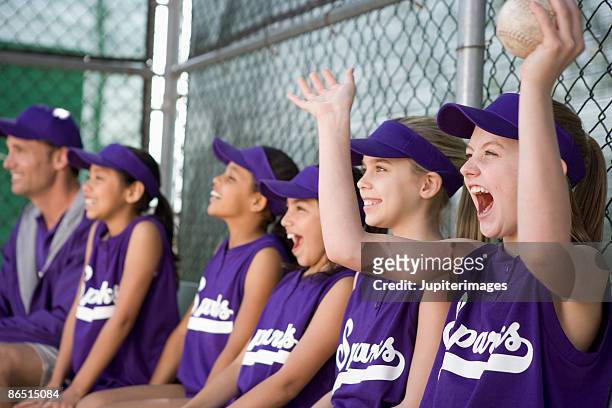 little league team in dugout cheering - baseball strip stock-fotos und bilder