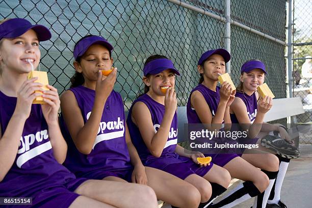 little league players drinking juice boxes and eating oranges - sports dugout fotografías e imágenes de stock