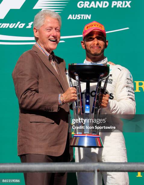 Former US President Bill Clinton and Lewis Hamilton with the winners trophy for the United States Grand Prix on October 22 at the Circuit of The...