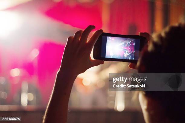 ventilator fotograferen door slimme telefoon terwijl u geniet van muziek concert - 逆光 stockfoto's en -beelden