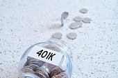 401k retiring plan concept with a glass jar full of coins on a marble counter top