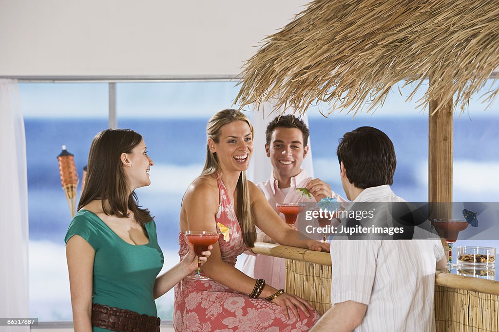 Group of people sitting at bar with cocktails