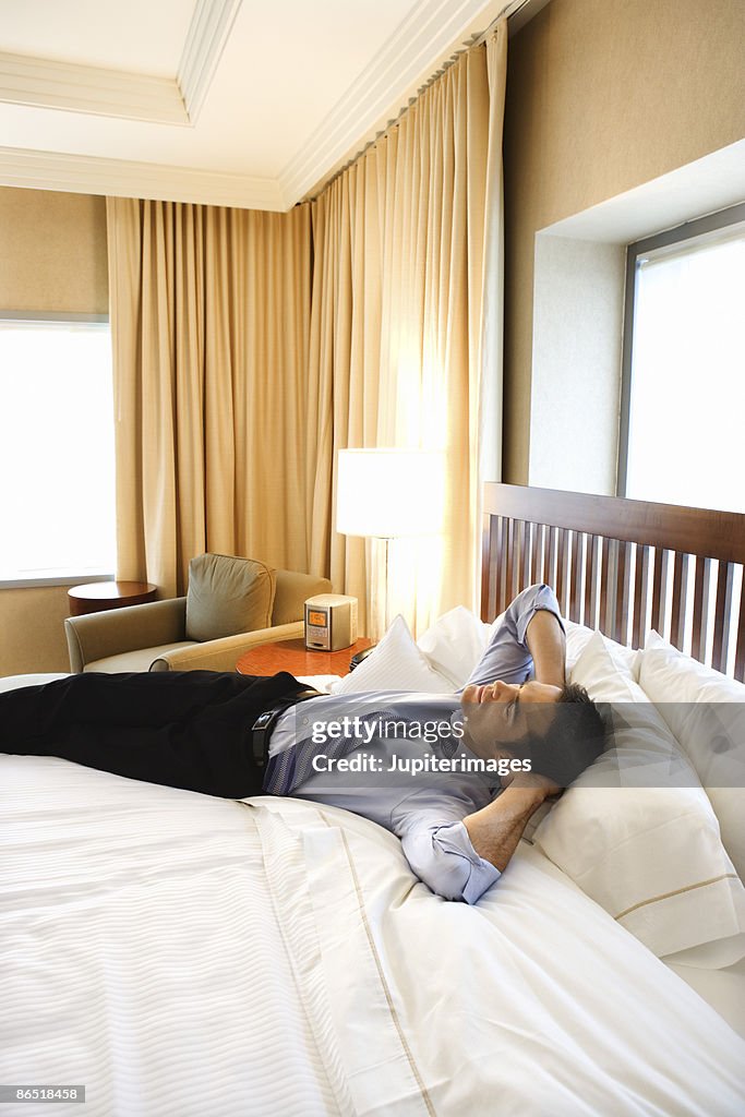 Businessman relaxing on bed in hotel room