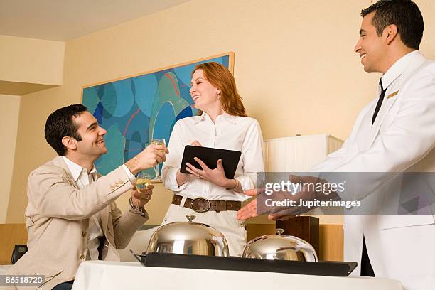 couple signing for hotel room service - domed tray photos et images de collection