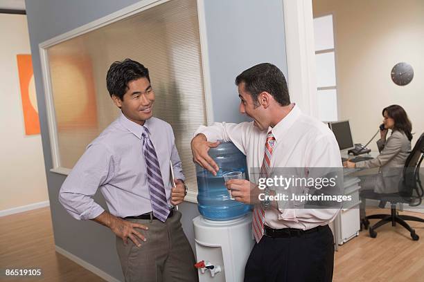 men standing at water cooler in office - water cooler stock pictures, royalty-free photos & images