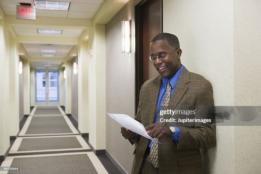 Businessman standing in hallway with document